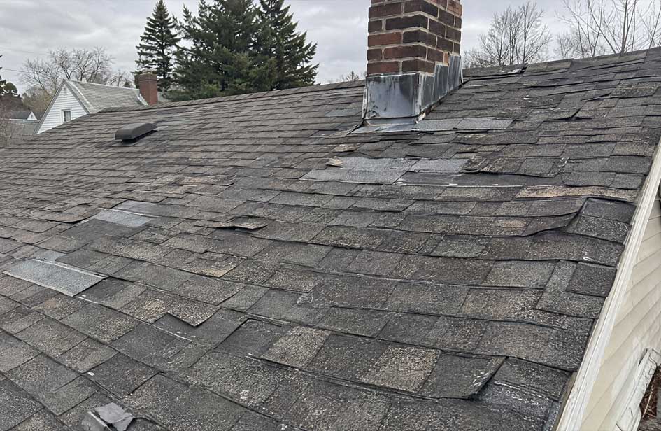 Older asphalt shingle roof showing widespread deterioration, previous repairs and damaged shingles