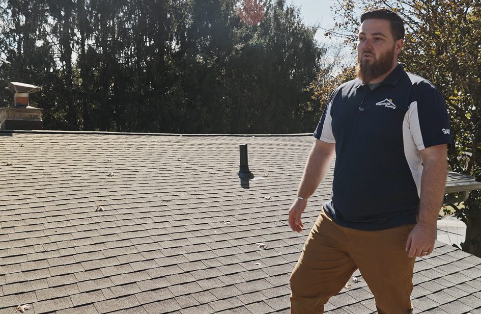 Jake Duncan of Sheppard Exteriors standing on the asphalt shingle roof during the Cheltenham Yew Road project walkthrough