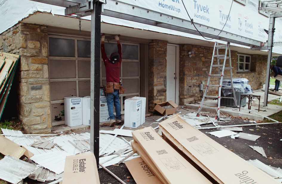 Sheppard Exteriors crew working on exterior details near garage doors and stone facade at the Cheltenham renovation