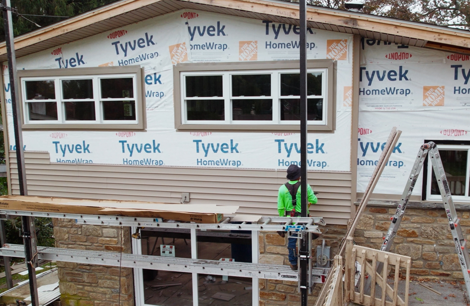 Sheppard Exteriors siding project with Tyvek HomeWrap white windows and partially installed siding above the original stone facade